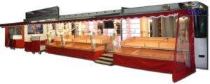 Camion marché textile panoramique avec chariots, étagères, cabines et enseigne motorisée. 12m de vente – Idéal lingerie et prêt-à-porter.