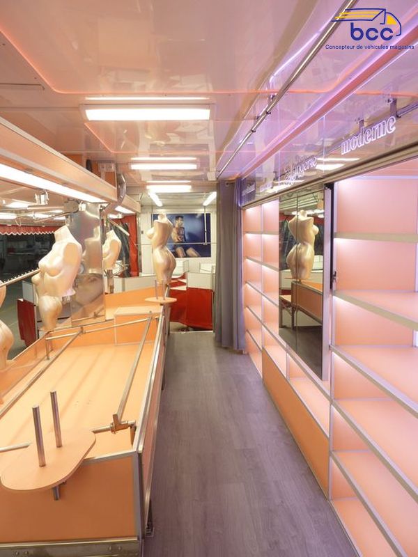 Camion marché textile panoramique avec chariots, étagères, cabines et enseigne motorisée. 12m de vente – Idéal lingerie et prêt-à-porter.
