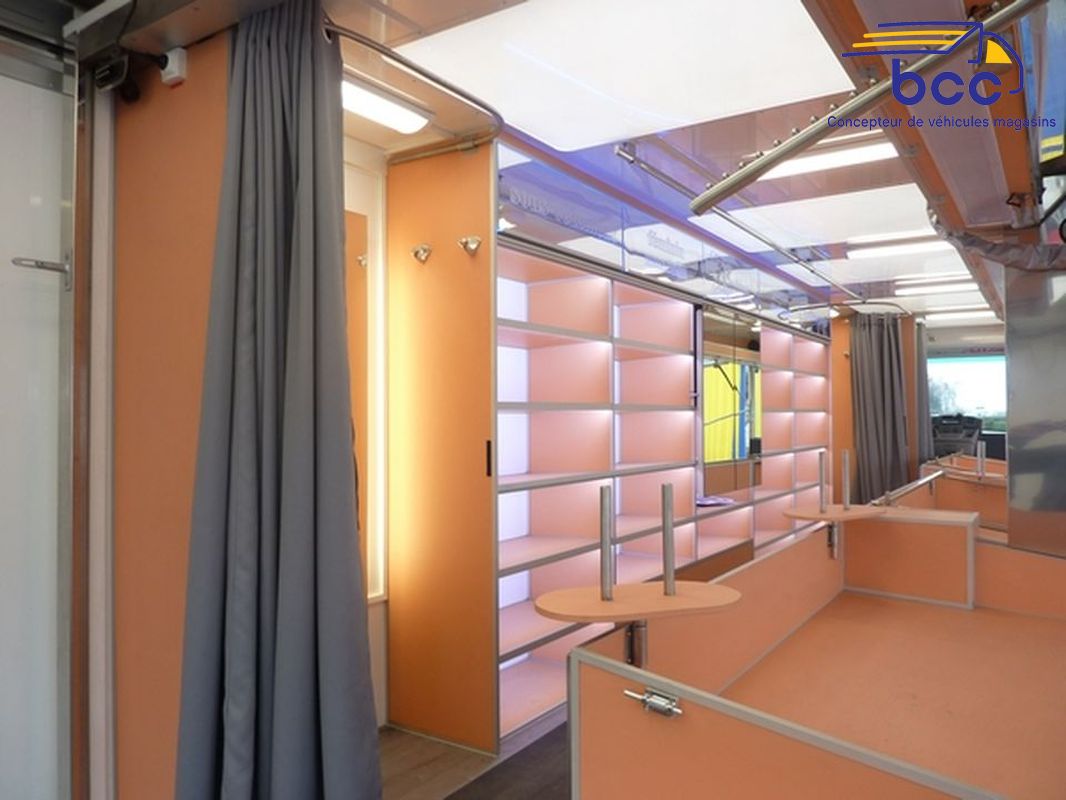Camion marché textile panoramique avec chariots, étagères, cabines et enseigne motorisée. 12m de vente – Idéal lingerie et prêt-à-porter.